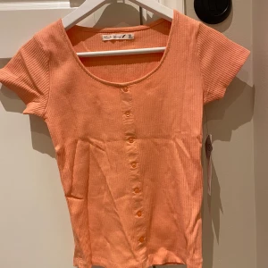 T-shirt - T-shirt med knappar hela vägen i aprikost från Ullared. Kan skickas om köpare står för frakt