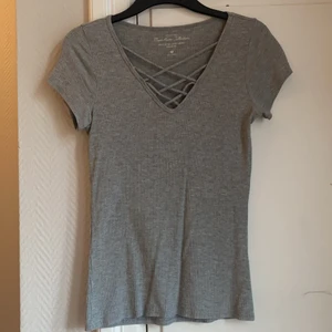 T-shirt - Grå t-shirt med korsad snörning. Köparen står för frakten, spårbart. 