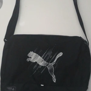 Svart axelbandsväska - Väldig bra skick förutom en fläck på baksidan. Skön och behändig väska där det får blats med dator och böcker. Går självklart även att använda som idrottsväska.