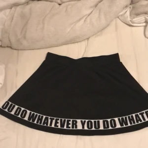 En svart kjol med text - Den är i sammet. Knappt använd men jätte skön att ha på sig. Lite kort. På texten står det ”YOU DO WHATEVER” 