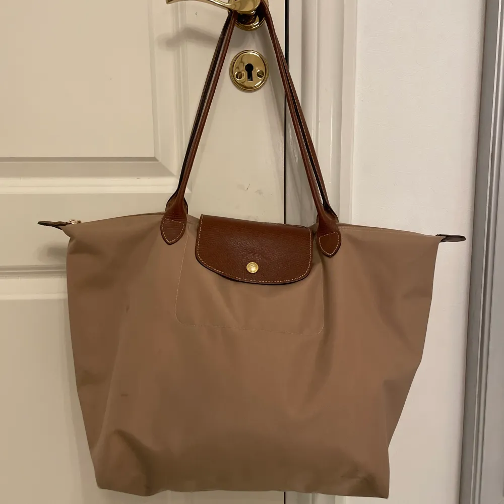 En beige Longchamp väska i använt skick med fläckar, ännu lite fler på undersidan också. Köpt för 1450kr💓(ÄKTA). Väskor.