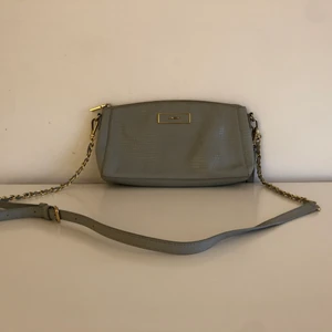 DKNY clutch bag - Säljer min fina gråa väska från DKNY då den inte längre kommer till användning tyvärr. Väl använd vilket syns (små märken här och var) men annars i väldigt bra skick. 