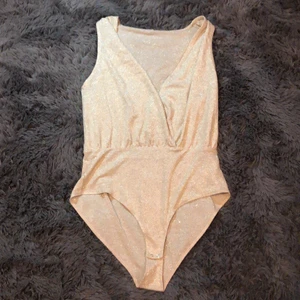 Glittrig body strl M - Jättefin glittrig body från & other stories. Perfekt till fest och lång urringning. Ena lappen är avklippt pga komfort men annars är den i bra skick. Frakt ingår i priset!!