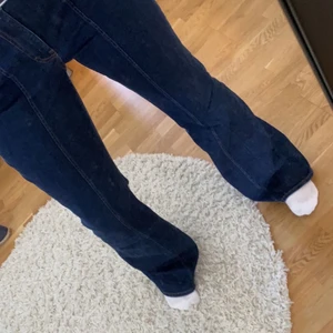 Mörkblåa jeans - Säljer ännu ett par jeans. Den här gången mörkblåa bootcut med detaljer på framsida lår. Använda ca 5 gånger så ser också helt oanvända ut. Storlek 42 och sitter lite löst på mig med storlek 38. 