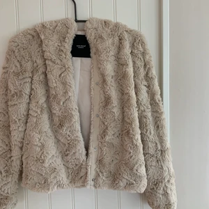Mysig jacka i fuskpäls stel S - Supersnygg jacka i fuskpäls med luva från VERO MODA. Jackan har en kort, rak passform och mjuk, skön kvalitet. Knappt använd och är i nyskick. Köpt för 500kr, säljs för 100kr.