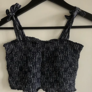 Mörkblått linne - Ett mörkblått linne med mönster från Nelly.com! Modellen på linnet är kort och den är liten i storleken skulle jag säga. Axelbanden går att knytas om. Bra skick! Säljer då den är för liten på mig💕