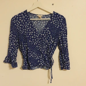 Blå tröja - Säljer nu en av mina favorittröjor då jag växt ur den. En mörkblå tröja som är omlott framtill och detta fästs med en hake, knäpp och en synlig söt rosett. Armarna är lite vida längst ner men utan att det blir störigt