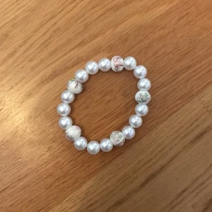 Pärlarmband  - Säljer ett pärlarmband med motiv på några pärlor, tror det ska föreställa blommor! Köparen betalar frakt 