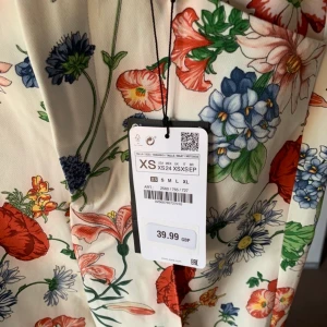 Zara blommig kostymbyxa - Blommiga kostymbyxor från Zara i storlek XS                         Jag köpte dessa på plick men dem passar tyvärr inte mig så jag har varken använt eller tvättat dem men kan inte tala för tidigare ägare! De ser däremot inte slitna ut alls så tippar på använda ett fåtal gånger!                                                                         Sista bilden är min egen och där står jag på tå för att visa längden då de är väldigt långa för mig som är 166cm