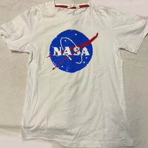 NASA t-shirt  - Vit t-shirt med NASA tryck i paljetter som är vändbart. Ev frakt betalas av köparen. 