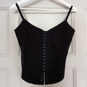 crop corset med meshdetaljer - en underbar korsett-topp i svart tyg med hylsor fram och detaljer i meshtyg där fram och i sidorna. storlek xs/x (bh-kupa a/b). materialet är semi-stretchigt. korsetten är i perfekt skick och sitter tajt med en mycket fin passform. ett riktigt fynd och ett linne som jag älskar men som tyvärr är aningen för litet för mig. jag möts upp i Malmö, annars betalar köparen en mindre summa för frakt. DMa gärna för frågor/detaljer/bilder osv. 💌