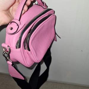 Small hot pink shoulder bag with black and silver details. Approximately 25x10x5 in dimensions. Never used!