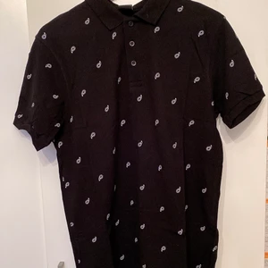 Svart Pikétröja Män - Pikétröja var köpt för 3 år sedan men använde mindre än 5 gånger. Tröjans längd är 70 cm och armlängd är 20 cm. Det är ”Slumfit” typ av tröja. Plagget kommer att blir nytvättad och styrka till leverans. Skriv om ni vill ha fler bilder eller frågor om plagget.