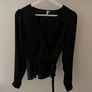 Supersöt blus från Nelly - Säljer denna jättefina blusen från Nelly i strl 34 då den tyvärr inte kommer till användning längre!! Materialet är blankt, liknande silke. Omlott med knyte i sidan samt litet spänne vid bysten så den ej blir så urringad. Använd fåtal gånger 💕✨ Köparen står för frakt!!!