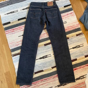 Levis jeans - Snygga Levis jeans i en cool mörkblå färg. Har en litenliten fläck som ej går bort ovanför knät. Midjemått: 75 cm. Innerbenslängd: ca 83 cm. 