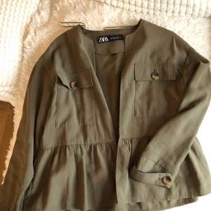 Militärgrön ”kofta”/tunn jacka från Zara. Den har volanger längs ner och stora knappar vid bröst fickan och vid ärmarna. använd två gånger och är som ny. ❗️köpare står för frakt❗️