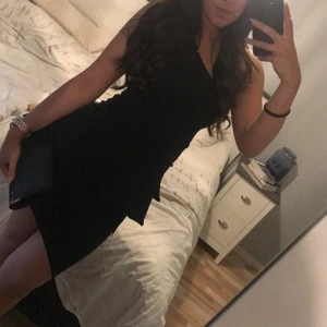 Klänning - Svart klänning med något band liknande så man kan knyta fram eller bak till på klänningen beroende på hur man vill ha det. Väldigt stretchig i materialet