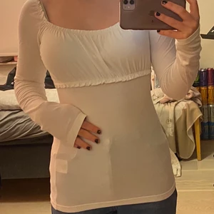 Vit tröja - Vit långärmadtröja med ”volang”. Använd en gång och är i jättefint skick! Dock lite svagt genomskinlig. Den är väldigt lång på mig som är 168 :) OBS frakten ingår INTE i priset