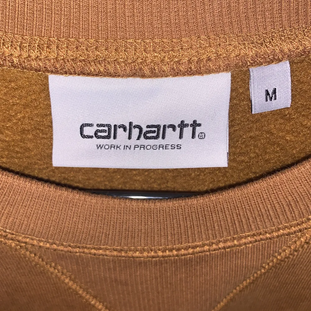 Jättesnygg Carhartt sweatshirt i nyskick. Något mer ”senapsfärgad” än vad som framgår på bilderna. Plain med logga på ärmen. Det är herrstorlek men funkar för båda. Skriv vid intresse. Inga fläckar endast skuggor på första bilden.. Tröjor & Koftor.