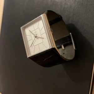 Klocka från Calvin Klein - Ett unisex arbandsur från CK.  Ca 3 cm bredd. Svart läderarmband. Fungerar utan anmärkning