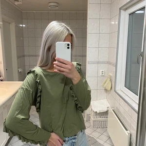 Grön långärmad  - Grön långärmad tröja med volanger. Köparen står för frakten!