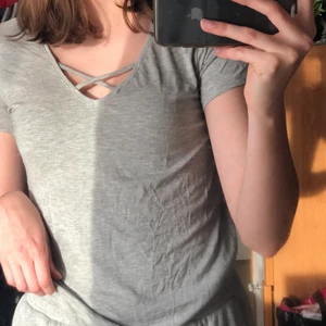 grå t-shirt - En grå enkel t-shirt med korsning där fram. Är i storlek S men passar både M och XS beroende på hur du vill att passformen ska vara. 