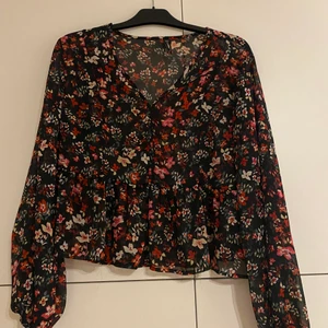 Blommig topp - Den är ganska genomskinlig men jättesöt. Den har ingen resår i midjan vilken gör den väldigt tajt om man har större byst. Den har ballongarmar. / Lina