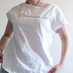 Vit t-shirt med text - En enkel vit t-shirt som är lite nära off The shoulder. Om man undrar så säger texten "I belive in women". Den är fult brukbar jag har bara tröttnat. Köpare står för frakt. 