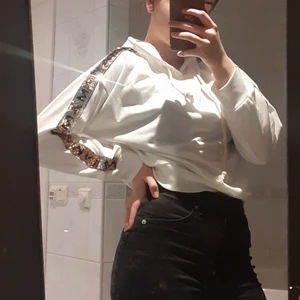 Hoddie - Vit hoddie med gul/silver glitter på sidorna går att dra glittret up och ner beroende på ifall man vill ha gul elr silver på sidorna, lite mer rep liknade snören som gör en fin detalj på tröjan