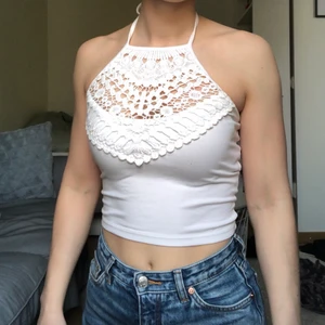 Vit halternecktopp - Vit crop top från Bikbok med halterneck i spets. Supersöt men kommer tyvärr inte till användning längre. Skriv vid frågor eller om ni vill ha fler bilder!