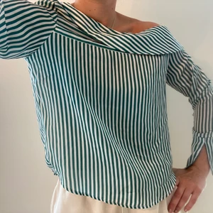 Grön randig blus från GinaTricot storlek 36 - Grön randig blus från Gina Tricot i storlek 36. Halv of shoulder och har slits på ärmarna. Fint skick, använd ett fåtal gånger. Köparen står för frakt