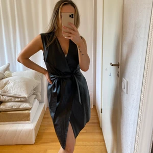 Skinnklänning storlek 36 - Supersnygg svart skinnklänning ifrån Nelly. (Ej äkta skinn). Storlek 36. Stängs med två knappar i midjan och ett skinnbälte. GRATIS FRAKT.