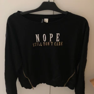 Svart tröja - Kort svart tröja med tryck och dragkedjor som detaljer