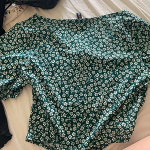 Grön topp med vita blommor - Toppen har en resor i mitten som du kan knyta åt. Väldigt somrig och modern. Aldrig använd då det var en present och jag inte tyckte den passade min kroppsform. 