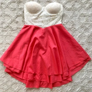 Sommarklänning/ miniklänning stl 36 - Sommarklänning från Club L i stl 36. Klänningen är vit och korallröd och stängs med en dragkedja i ryggen. Den har gummi kring bysten för bättre fäste. Klänningen är använd en gång och har en del spår av brunpuder invändigt, men bör gå bort i tvätt. :)