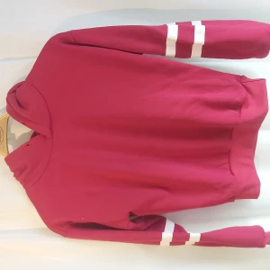 Röd hoodie - Röd hoodie men två vita sträck på varje ärm. Är i bra skick men lite noprig på änden av ärmarna.