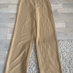 Vida beiga kostymbyxor från bik bok i storlek 36 - Jag säljer mina vida beiga kostymbyxor från bik bok, jag är 165 cm lång och på mig passar storlek 36 jättebra.