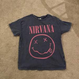 Blå T-shirt med en rosa smile och det står NIRVANA. Jätte bra skick har använt få tal gånger, inga fläckar. 