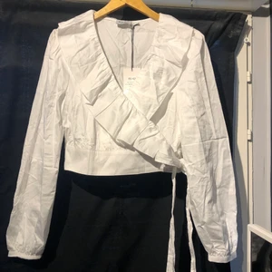 Omlott blus  - En superfin vit omlott blus. Aldirg använt den tyvärr då det inte riktigt är min stil. Storlek 42 men går att justera runt kroppen efter storlek så passar även storlek 40. Säljer en likadan i svart. Kan skickas, köparen står för frakten 