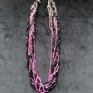 Halsband med lila och svarta pärlor. På bild nr 3 ser ni den ungefärliga längden. Säljes till den som lagt det högsta budet i kommentarsfältet. Porto på 24 kr tillkommer 