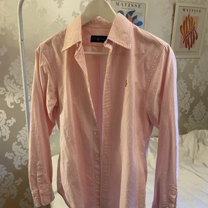 Polo Ralph Lauren skjorta  - Klassisk skjorta från Polo Ralph Lauren. Rosa och vitrandig. Fint skick. Såklart äkta,köpt i butik i USA.