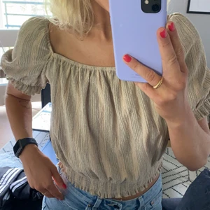 Topp från H&M. - Kortärmad och croppad topp från H&M. Beige med svarta linjer. Storlek L. Stretchigt material och liten i storleken.