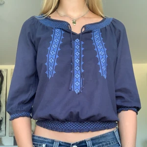 Söt blus med brodering - En jättefin blå blus från H&M. Den har fina broderingar i fram och resår kring ärmarna och midjan. Fint skick!  I storlek 36.