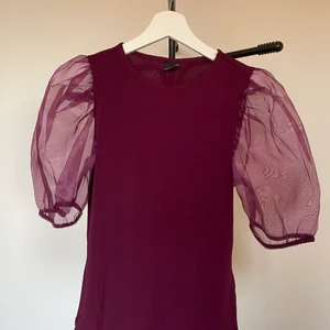 Topp med meshärmar  - En topp med puffiga ärmar i en fin plommonfärg. Använd 1 gång så den är i nyskick. Tröjan är väldigt mjuk och bekväm! Frakt tillkommer!