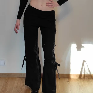 Lågmidjade cargo pants - Vårrensning!!! Byxorna har Snörning på benen som man kan dra åt så det blir bootcut. De är avtagbara och då blir dem rakare i modellen. Fyra framfickor och 2 bakfickor alla med dragkedja!!!! (Midjemått 72 cm)