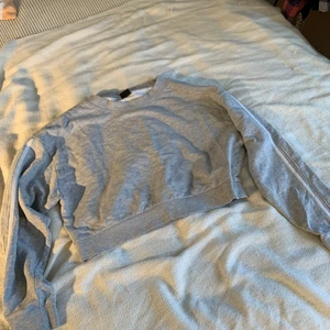 Grå magtröja - Grå magtröja i bomull med med vita ränder på ärmarna.