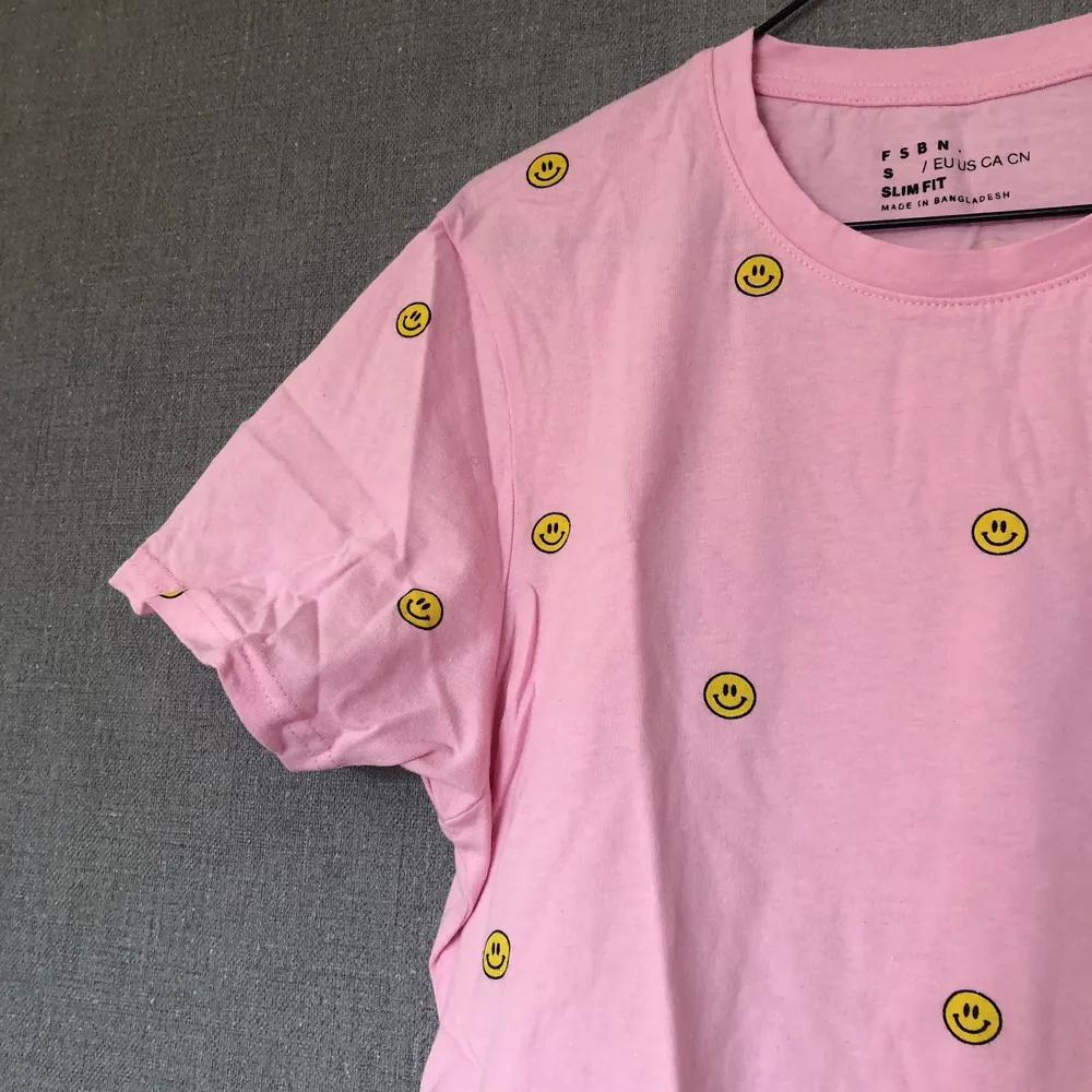 • Färgglad & härlig tisha! Go rosa nyans med klargula smileys all over. Passar till det mesta, fin färgklick i vardagen! • Storlek: M, herr • 100% bomull • Använd ett fåtal gånger, fint skick! Lite luddig i tyget efter tvätt. • +Frakt: 51kr spårbart  . T-shirts.