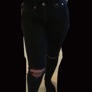 Svarta Jeans - Svarta tajta jeans med slitningar vid knäna