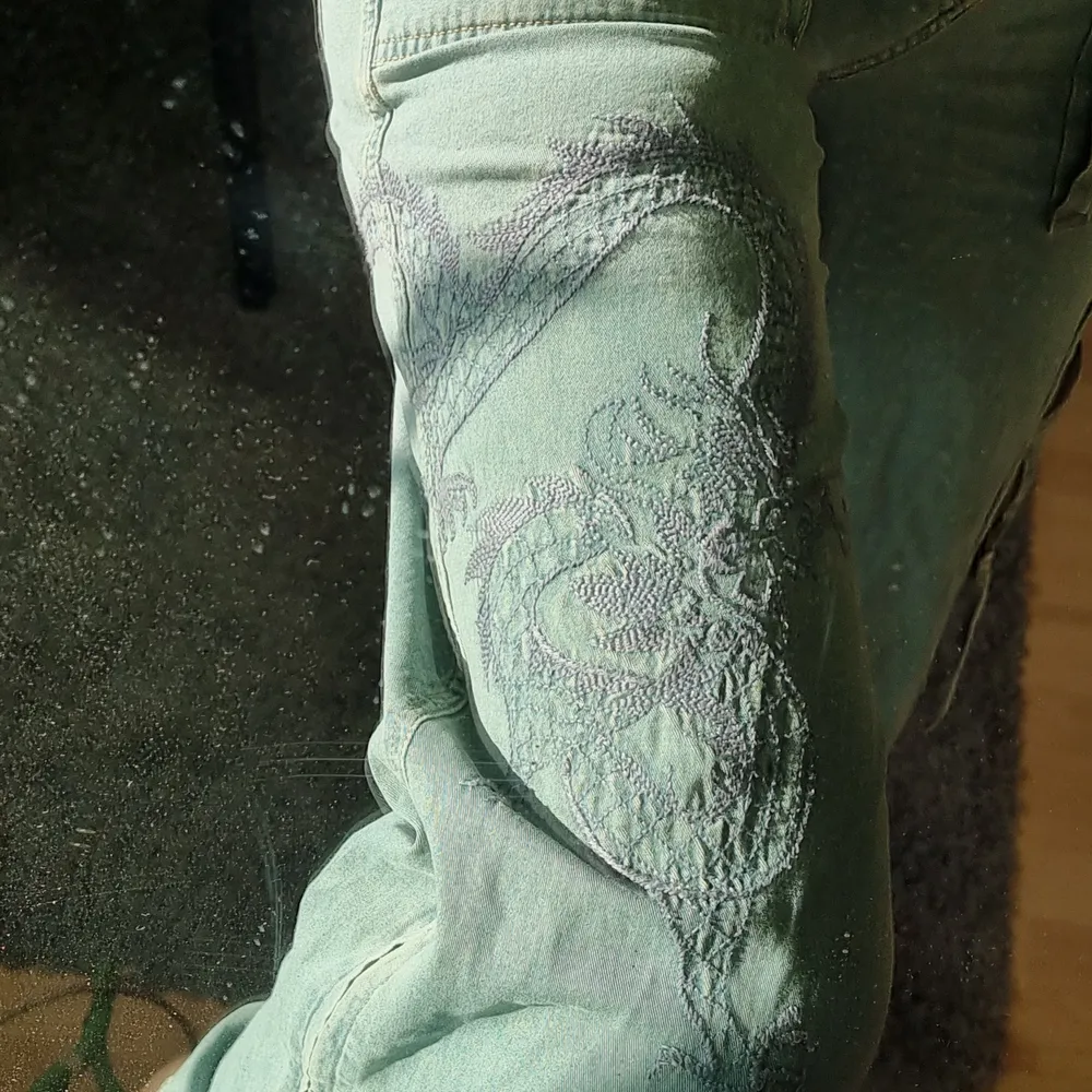 Ljust blågröna byxor i tyg🐉broderad drake på ena byxbenet, dragkedjor på sidan av benen så man kan ha 