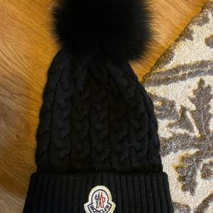 Jättefin moncler mössa till vintern. Väldigt skön och jätte fin fluff på pälsen. Dock så är det fake men efterliknar den äkta. Det är onesize och väldigt stretchig. Endast använd en vinter ett par få gånger. Kan användas för både tjejer och killar då pälsen går att ta av. Bud ligger just nu på 350kr